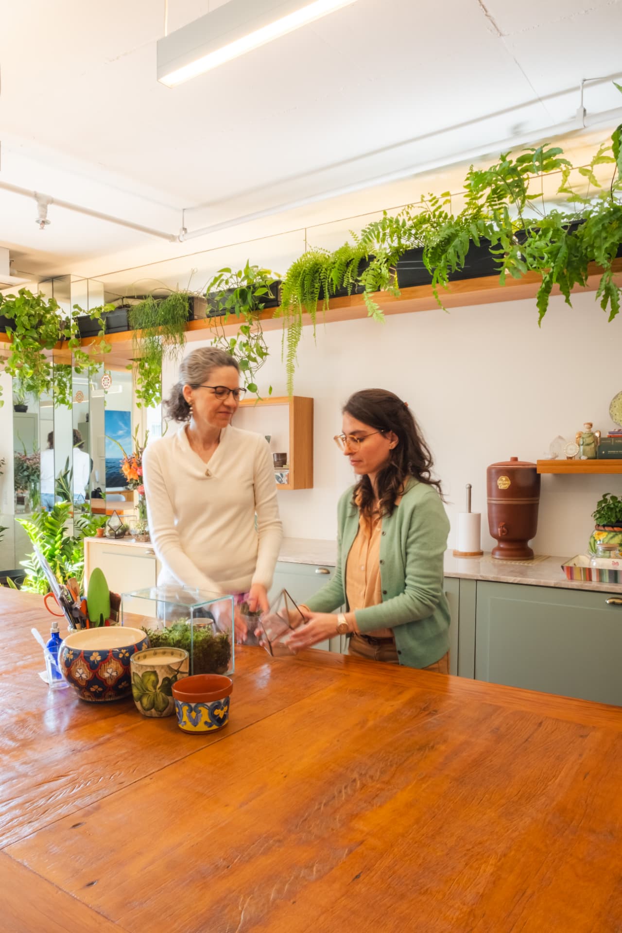 Duas mulheres cuidando de terrários em um ambiente com plantas da Natural Estar B.E.N.